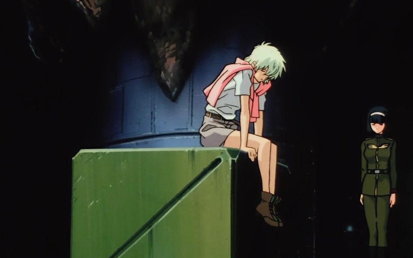 Still from Mobile Suit Gundam: The 08th MS Team of Aina looking forlorn wearing a khaki shorts, boots, white t-shirt, and a pink sweater draped around her shoulders