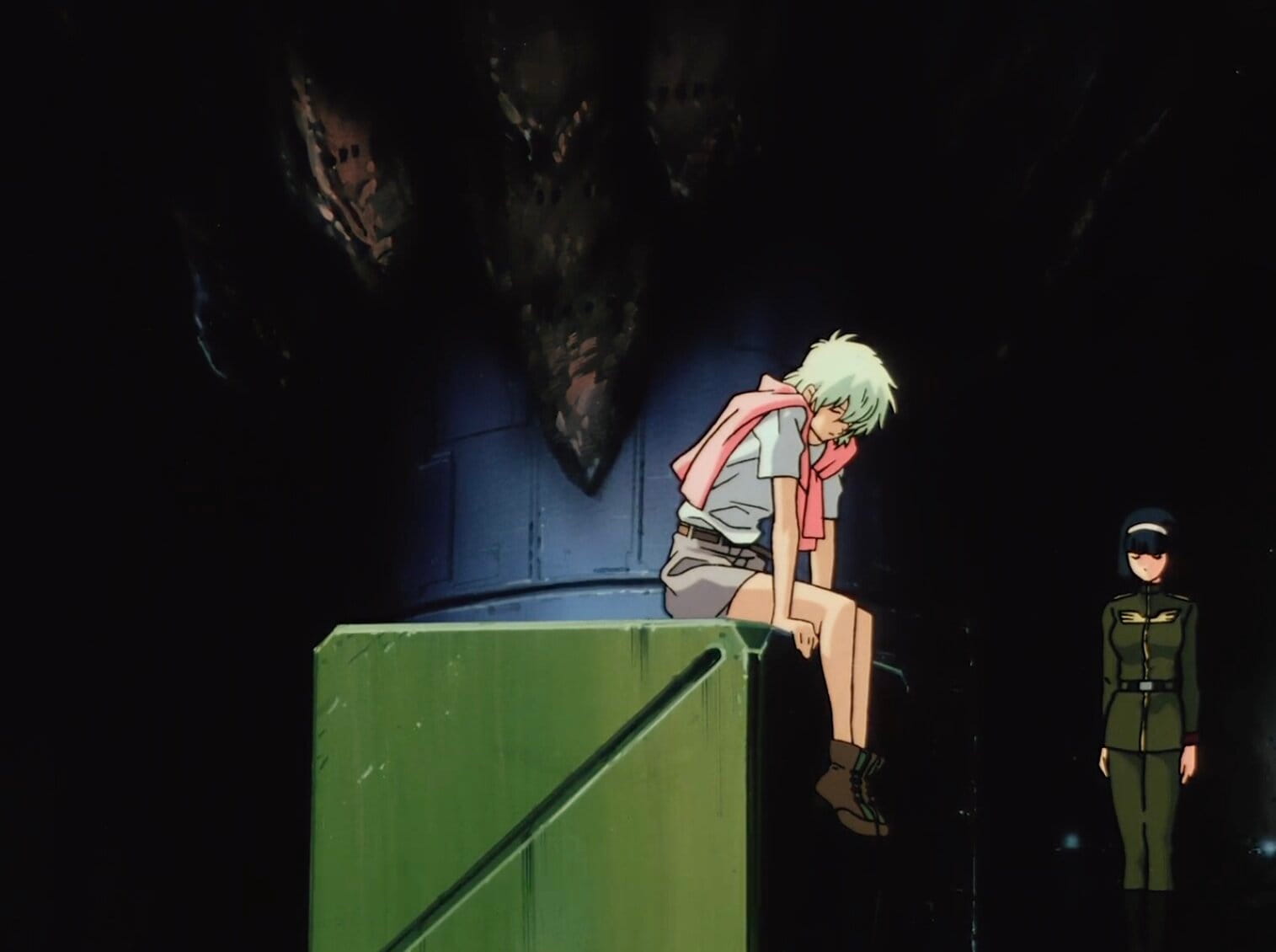 Still from Mobile Suit Gundam: The 08th MS Team with Aina looking forlorn wearing a khaki shorts, boots, white t-shirt, and a pink sweater draped around her shoulders